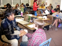 Teacher assisting student in busy classroom